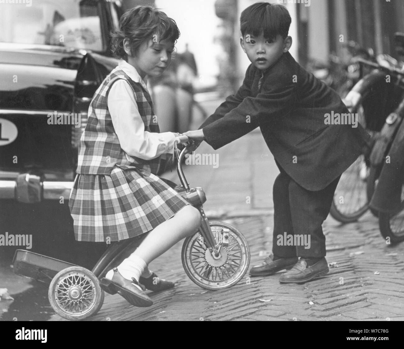 Children playing with a tricycle, c1960s Stock Photo - Alamy