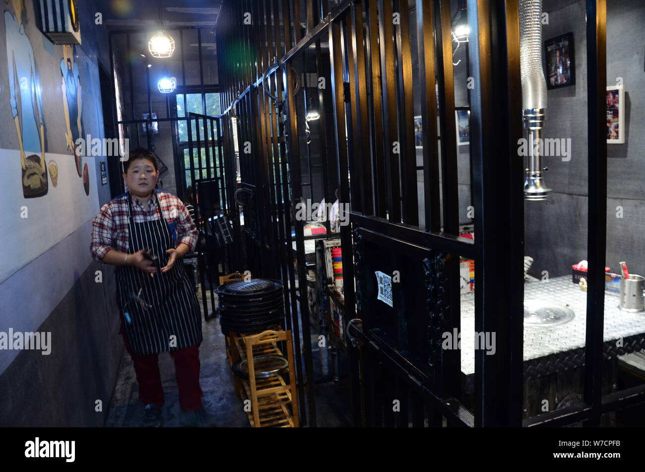 A waiter walks past cell-like dining rooms at a prison-themed restaurant in Weifang city, east China's Shandong province, 22 October 2017.   A new pri Stock Photo