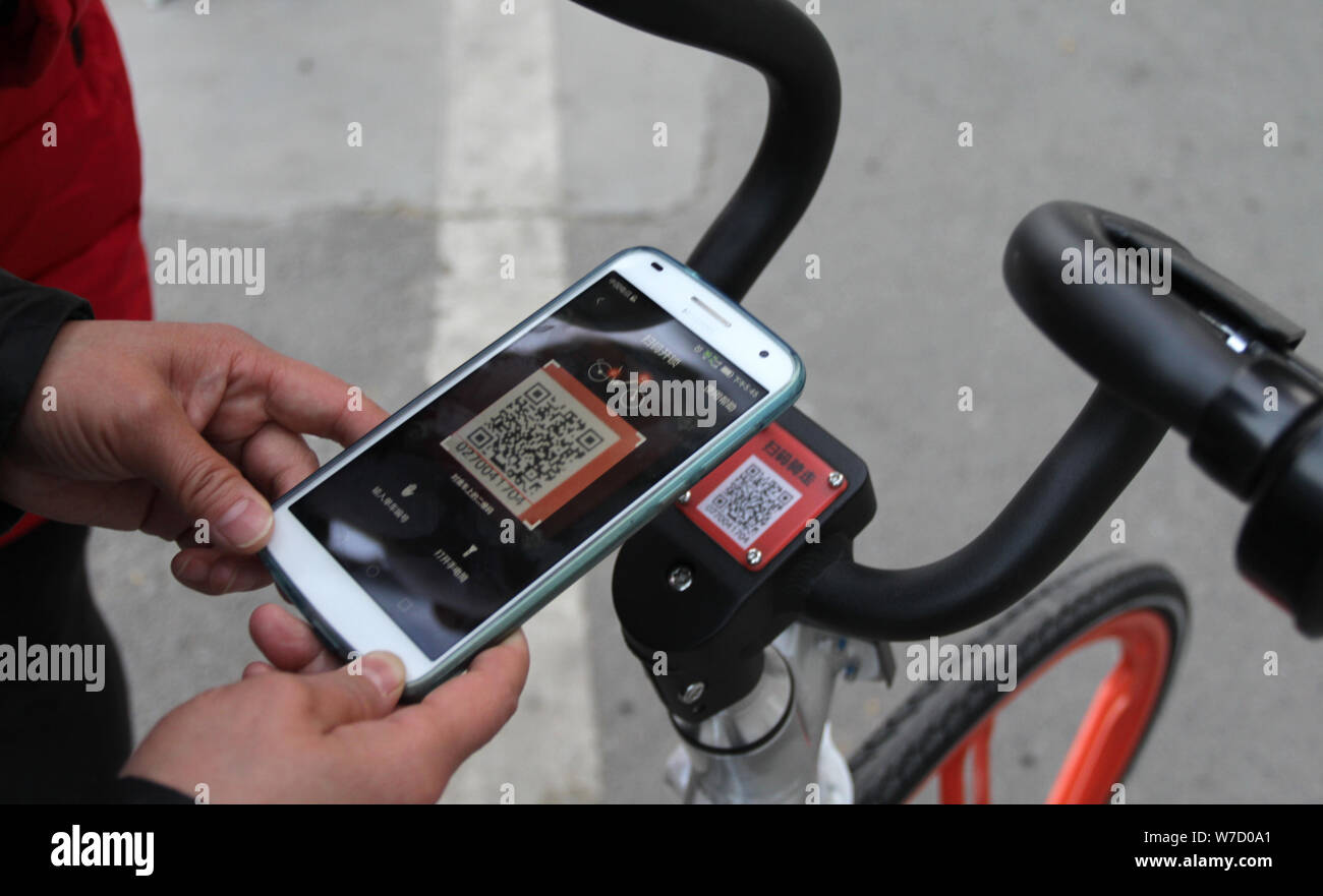 A person scanning a QR code on a shared bike with their smartphone.