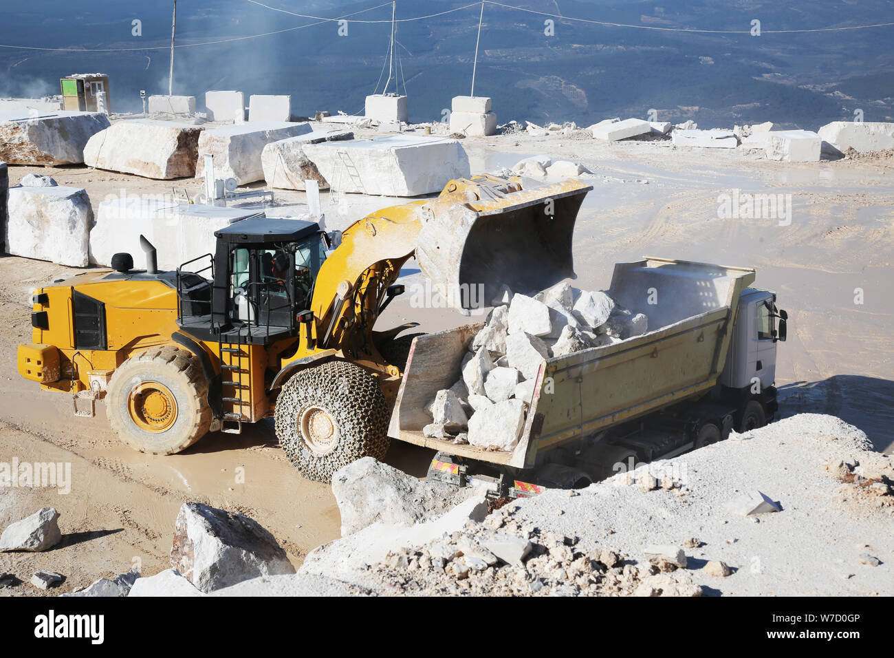 A loader working in marble quarry. Loader carrying marble block. Heavy