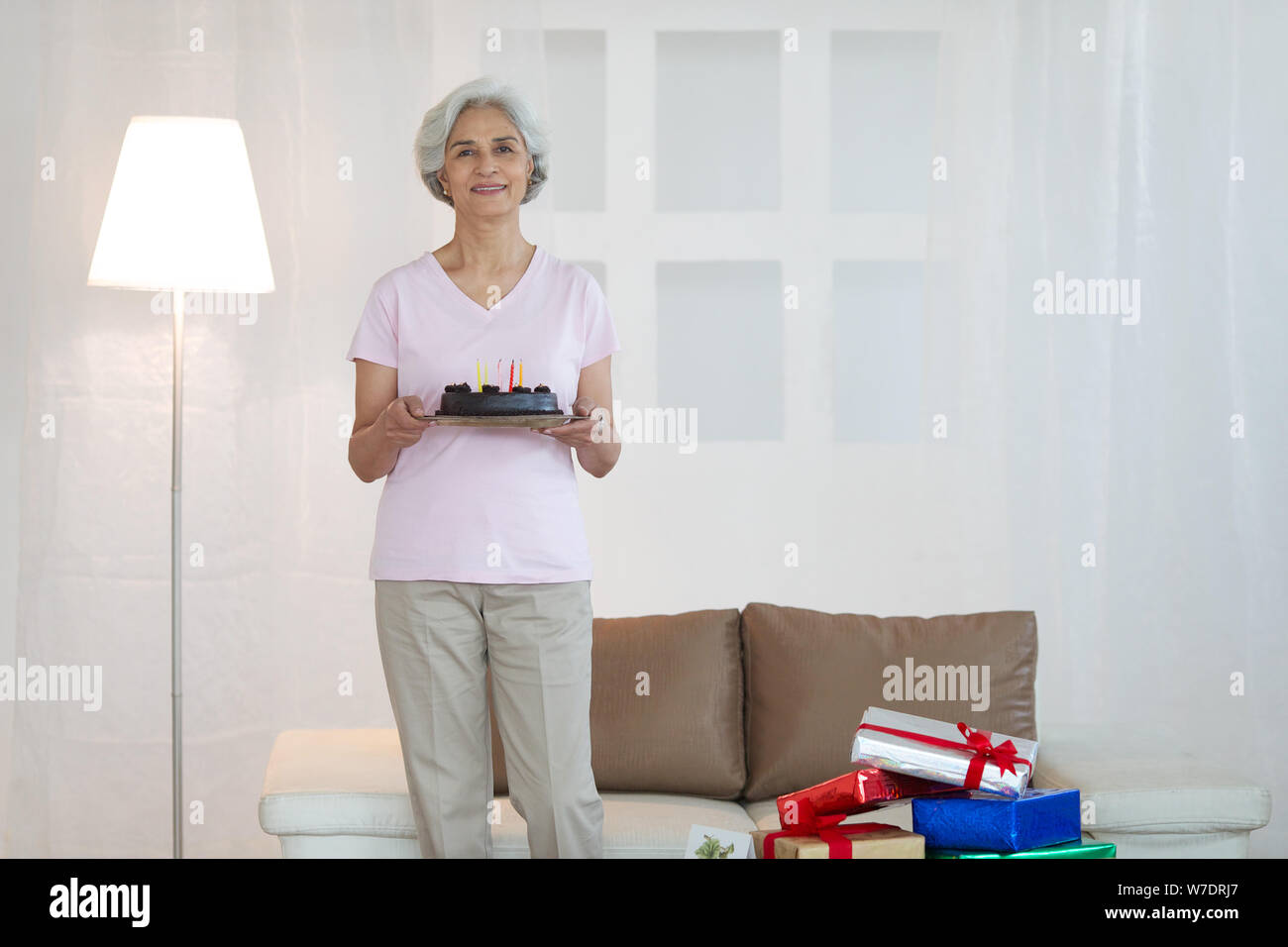 Old woman holding birthday cake and smiling Stock Photo - Alamy