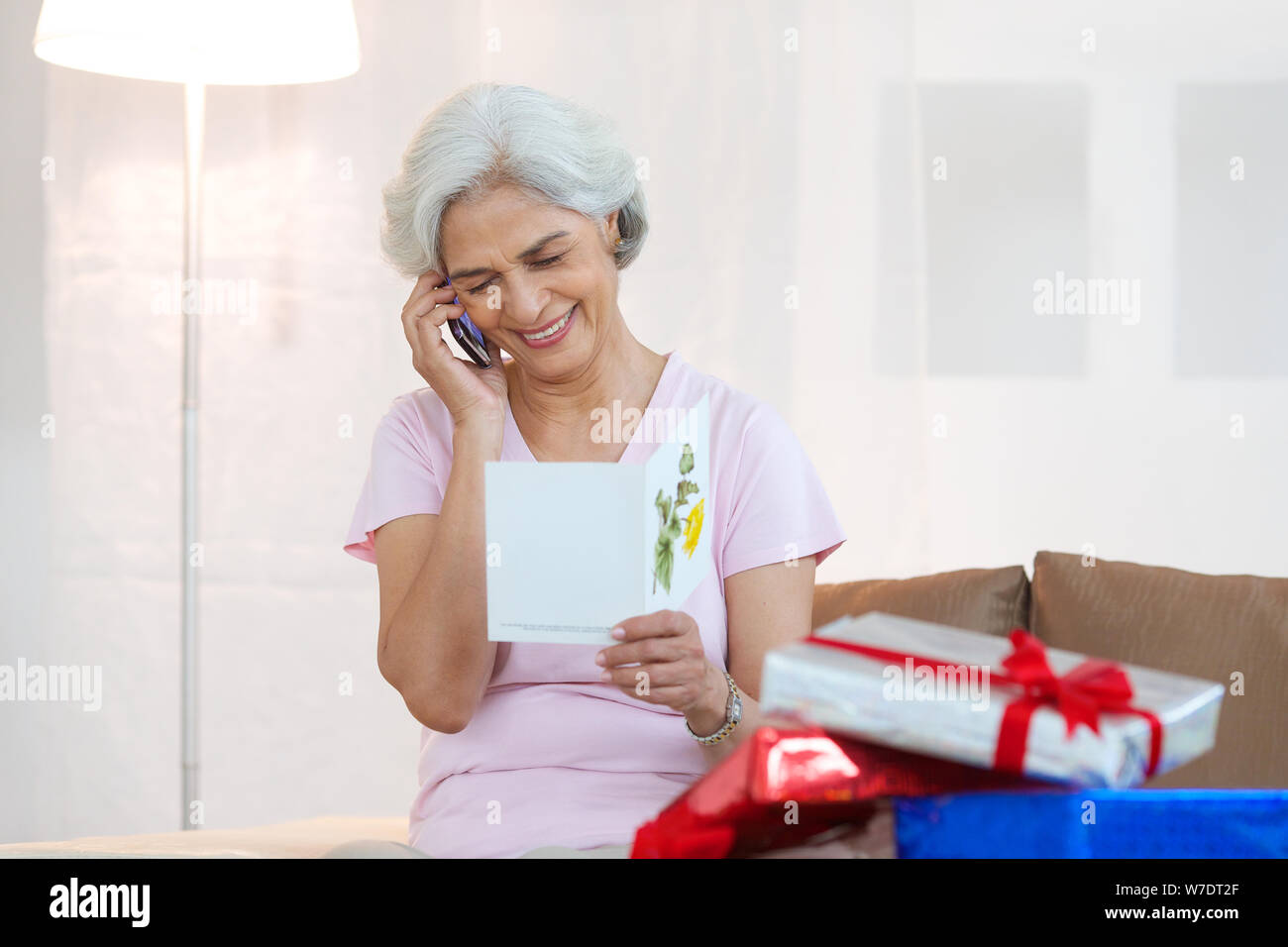 Old woman talking on mobile phone and reading birthday card Stock Photo ...