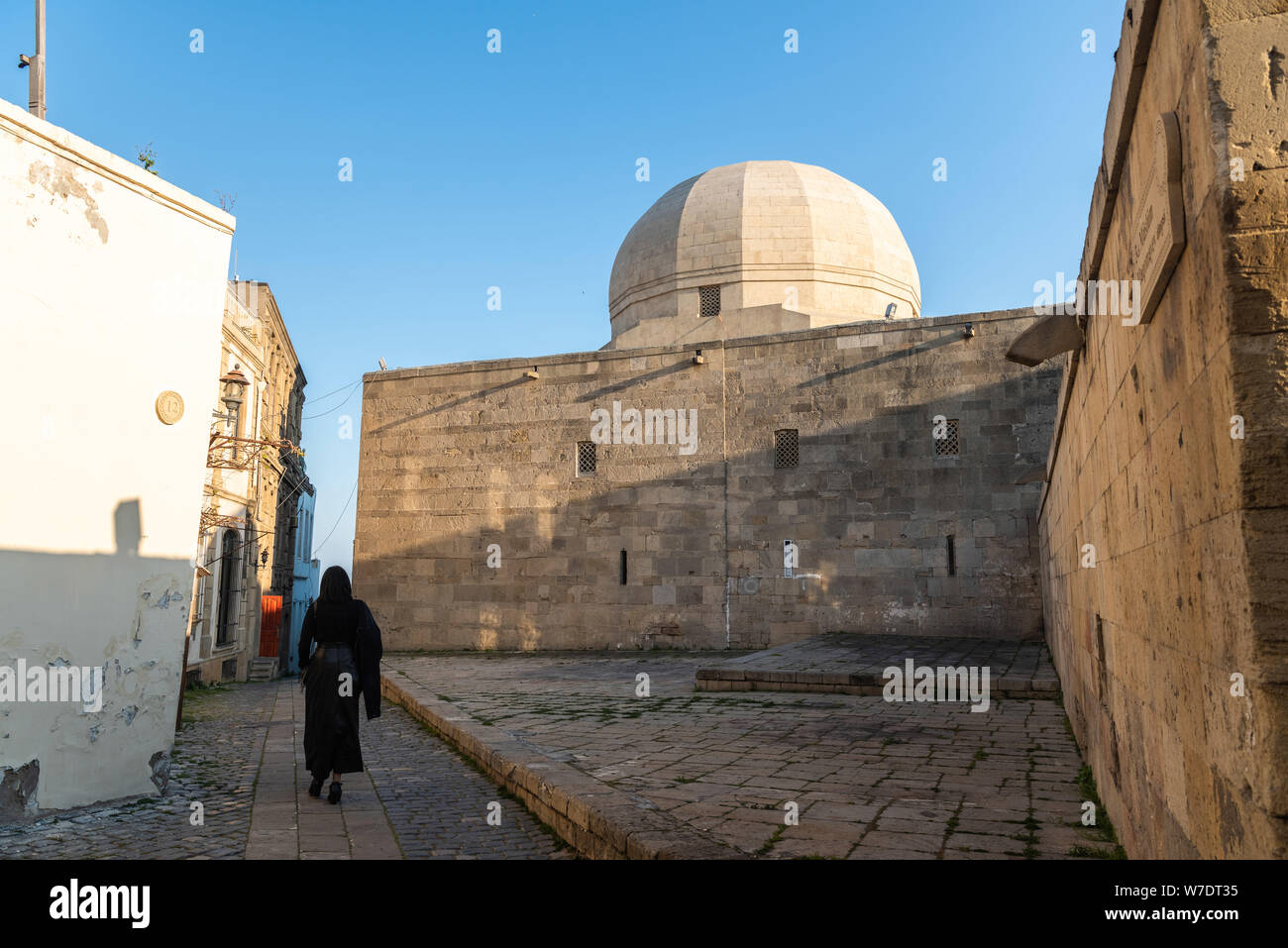 Street view in the Icherisheher old town of Baku, Azerbaijan, with exterior wall of the Palace of the Shirvanshahs building and unidentifiable figure Stock Photo