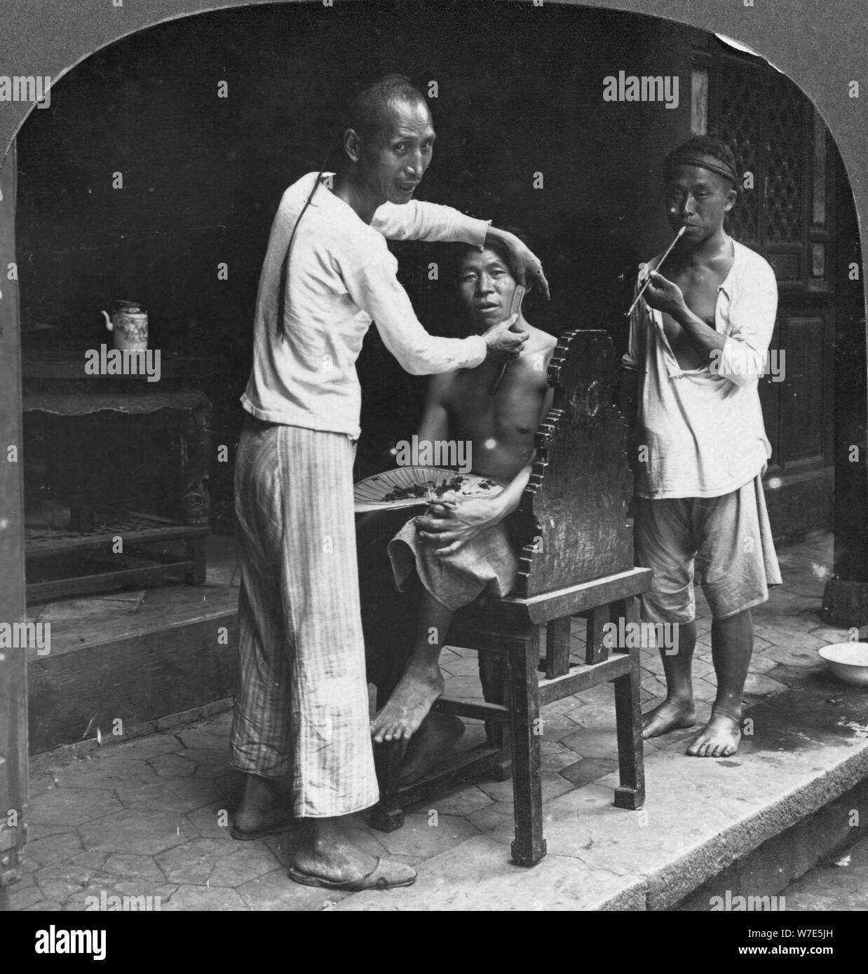 A Chinese barber at Bhamo, Burma, 1908. Artist: Stereo Travel Co Stock Photo