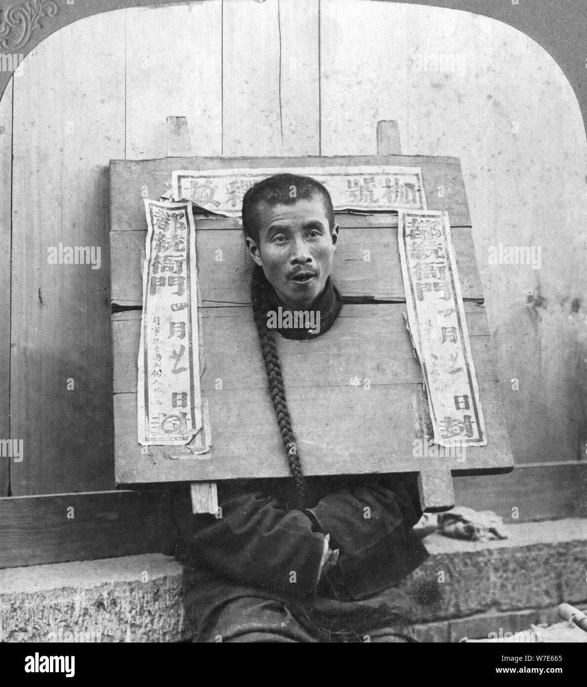 'Chinese prisoner in the cangue placarded with the record of his crime', China, 1902. Artist: CH Graves Stock Photo