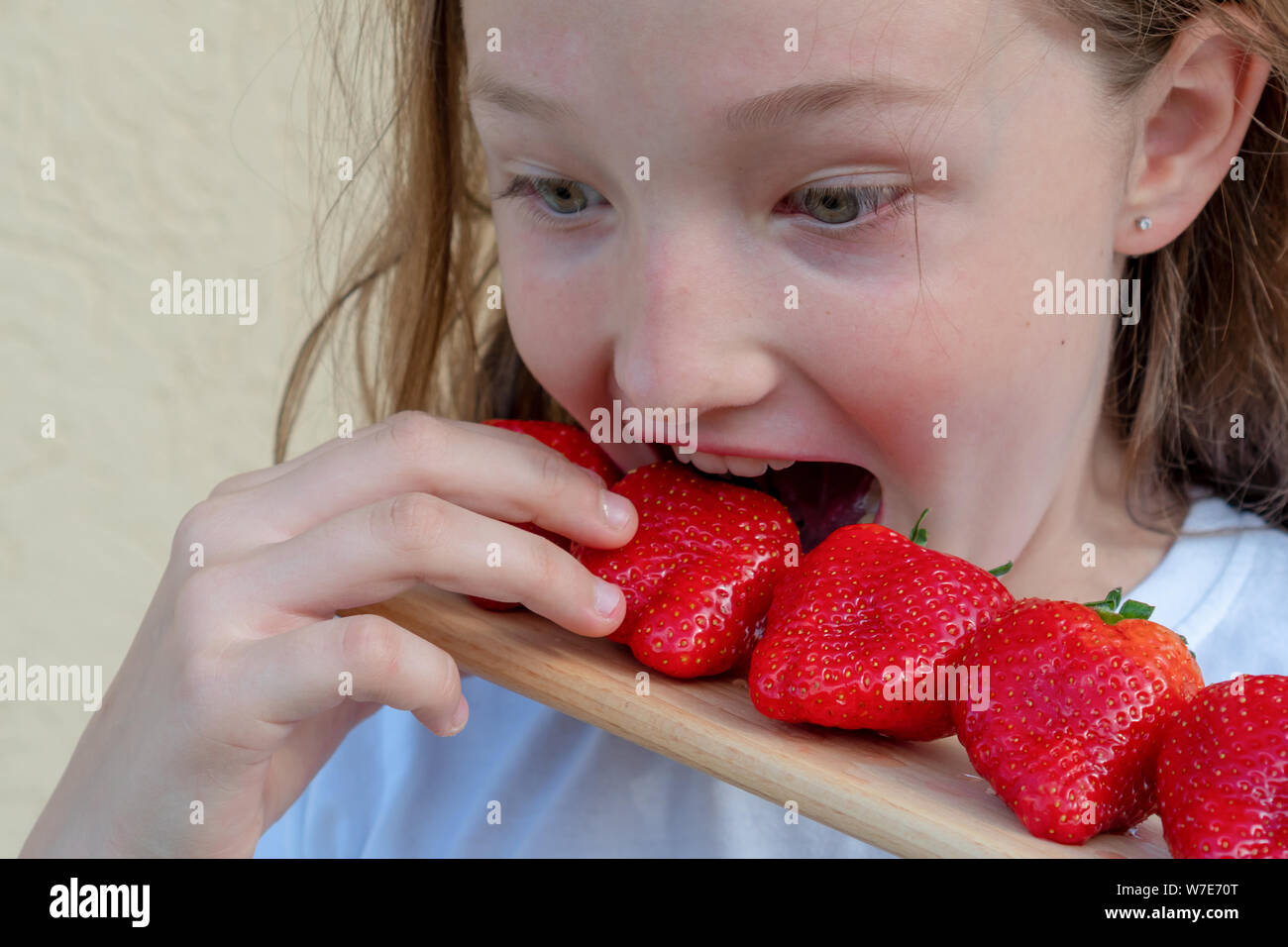 A young girl eats strawberries. Allergy in a child. Red face from