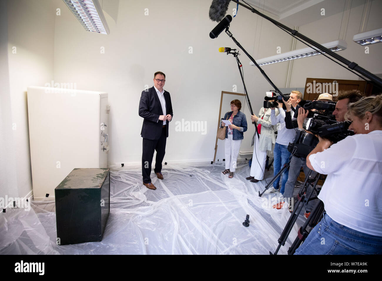 06 August 2019, Schleswig-Holstein, Lübeck: Jan Lindenau (SPD), mayor of Lübeck, stands in a room with two locked safes at a press event in the town hall. Using a fine picking tool and heavy equipment, two security technicians opened the safes in Lübeck's town hall on Tuesday, which had been unnoticed for decades. According to the city, the contents of the safes, which probably date from the 1950s, were unknown. Photo: Christian Charisius/dpa Stock Photo