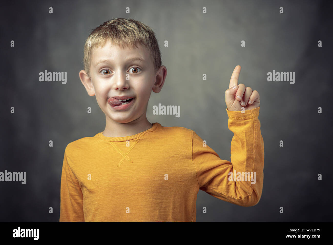 Funny portrait of a 6 year old Caucasian child with his tongue sticking out. shot taken in the studio. Stock Photo