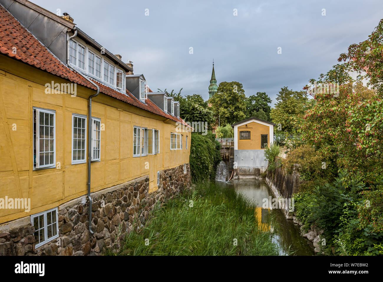 Canal along yellow buildings at the scenic town Frederiksvaerk, Denmark, July 30, 2019 Stock Photo