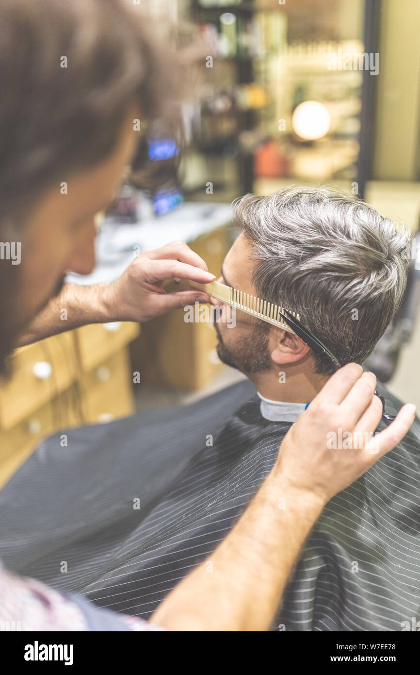 Hairdresser styling man hair in barbershop Stock Photo