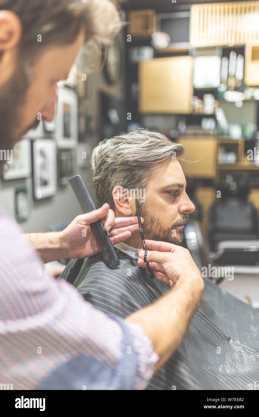 Man in barber chair, hairdresser styling his hair. Stock Photo
