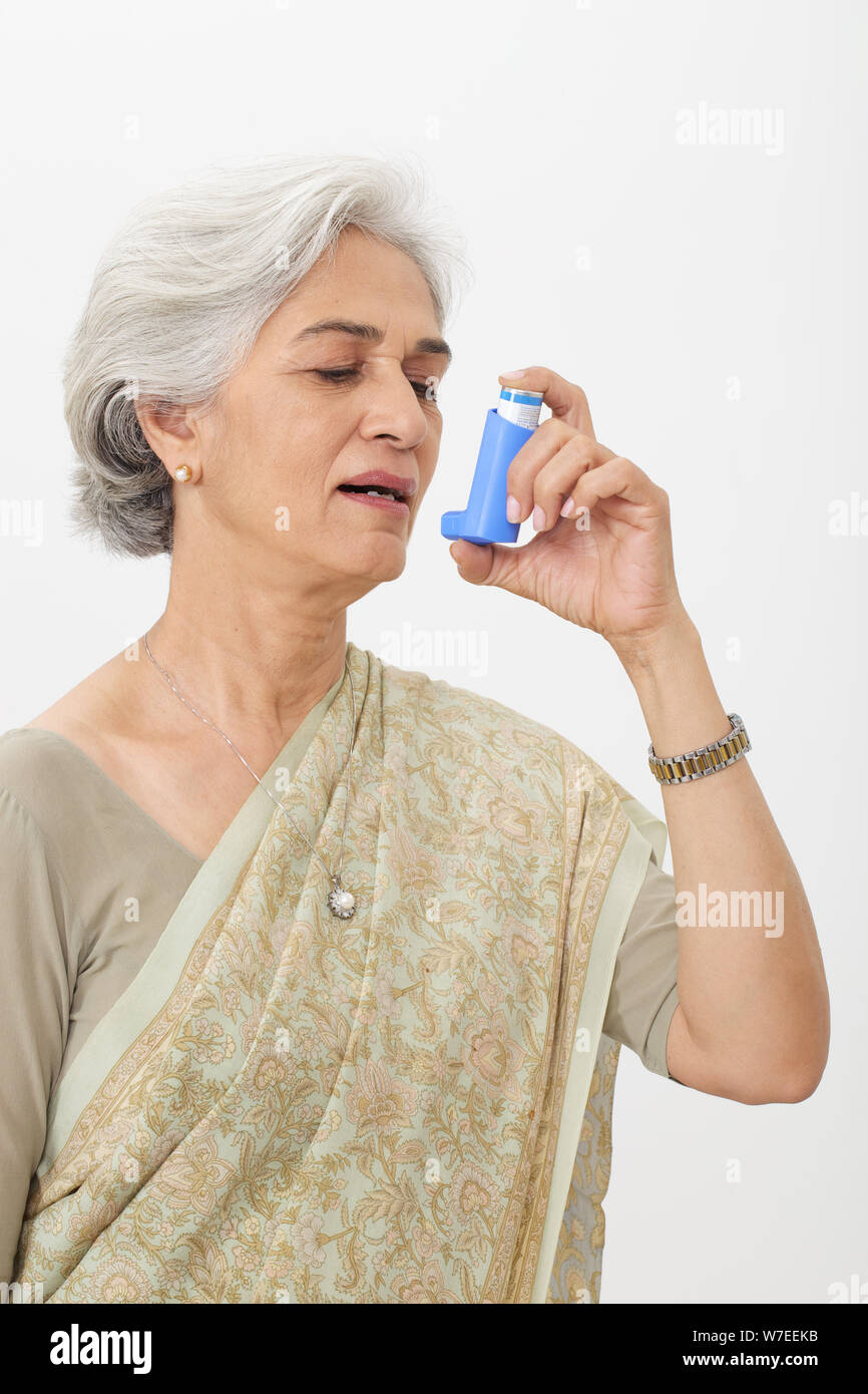 Old woman using asthma inhaler Stock Photo