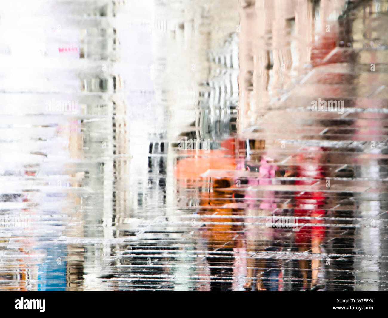 Abstract blurry background of reflection shadow silhouette in a puddle, of people walking alone in the summer city rain Stock Photo