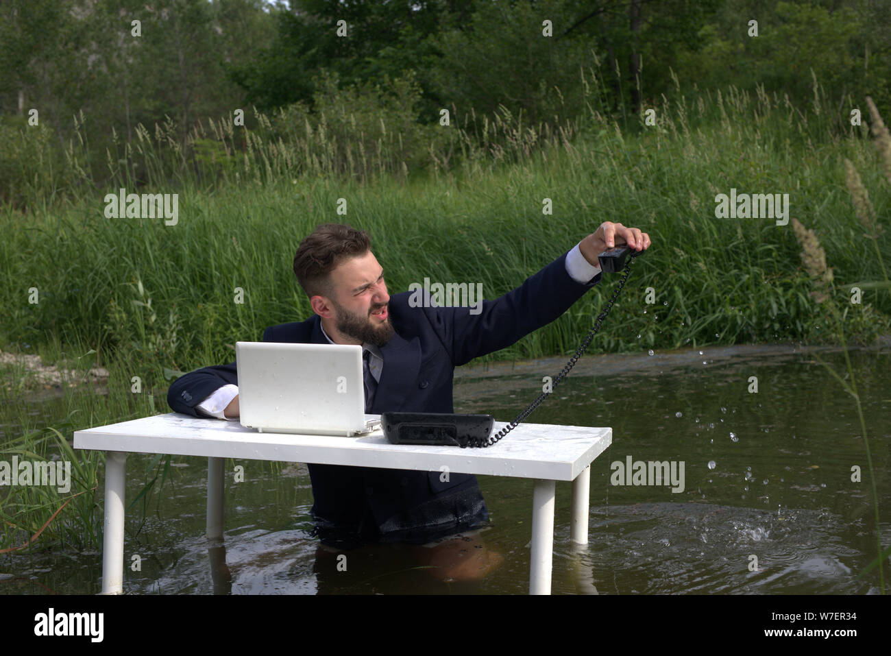tired worker, manager, call center employee drowned or threw the phone into the water. unloved office work Stock Photo
