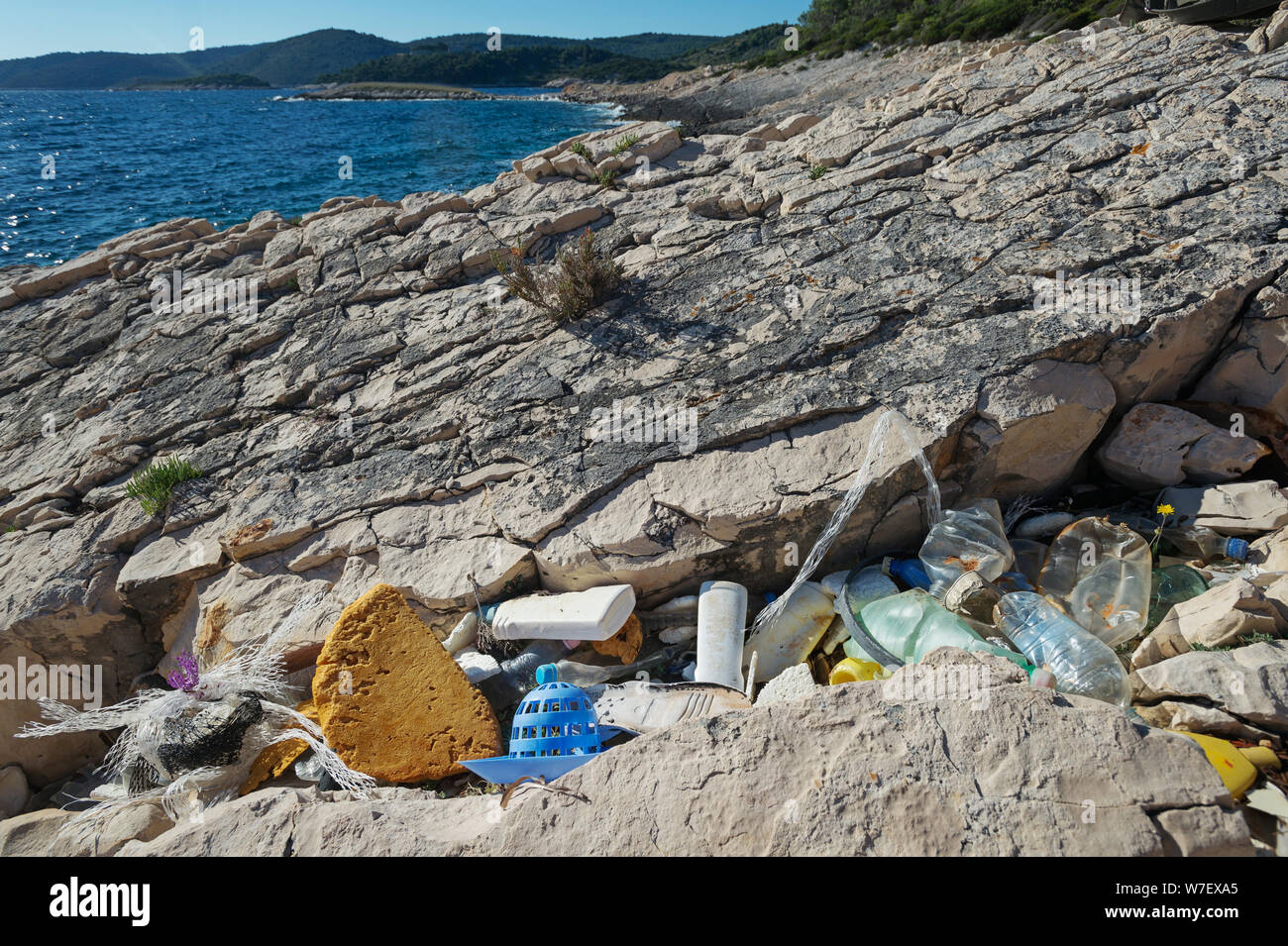 Marine debris accumulates heavily along seashores. Plastic bottles and other garbage washed out on coast. Plastic waste tide, sea pollution. Stock Photo