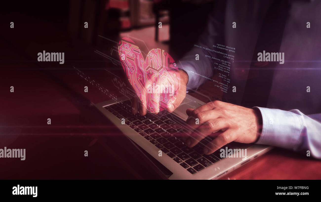 Man typing on laptop with cybernetic heart hologram screen over keyboard. Love, cyber dating, romantic, health and cardiology futuristic concept. Natu Stock Photo