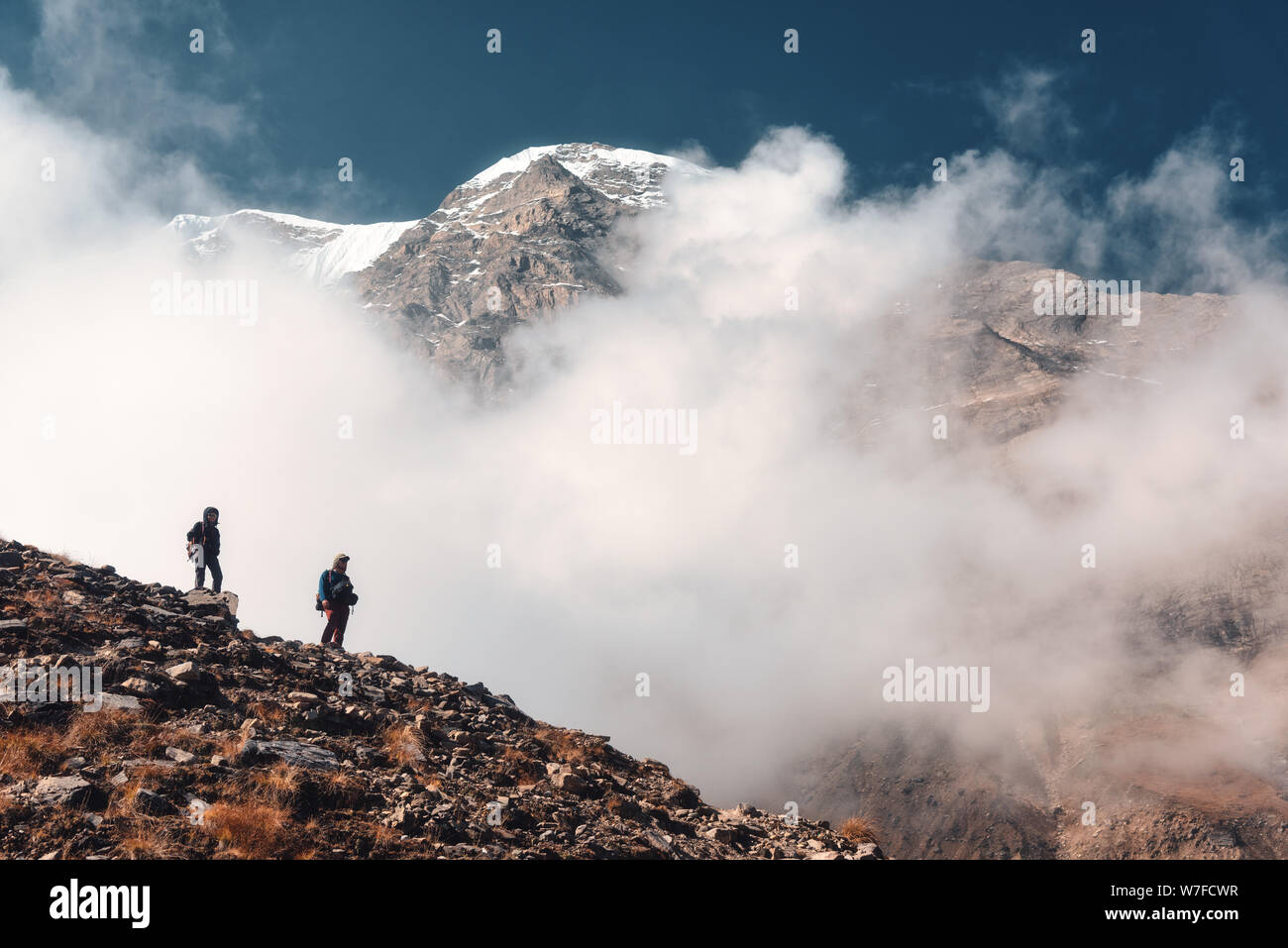 Standing people on the mountain trail in low clouds Stock Photo