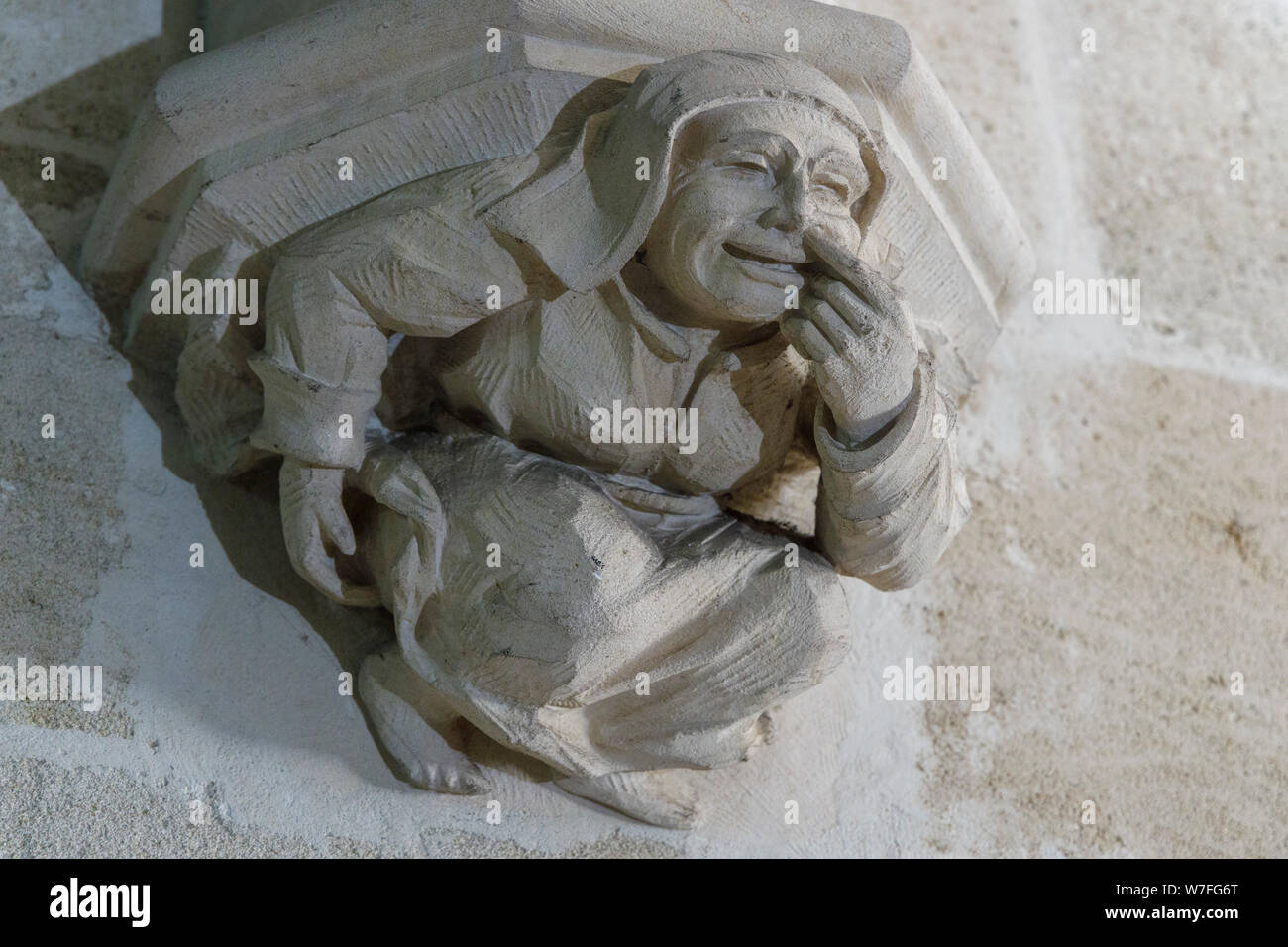 Irreverant gargoyle sculpture on the stairwell of Libourne Town Hall, Bordeaux, Nouvelle-Aquitaine, France. Friar picking his nose. Stock Photo