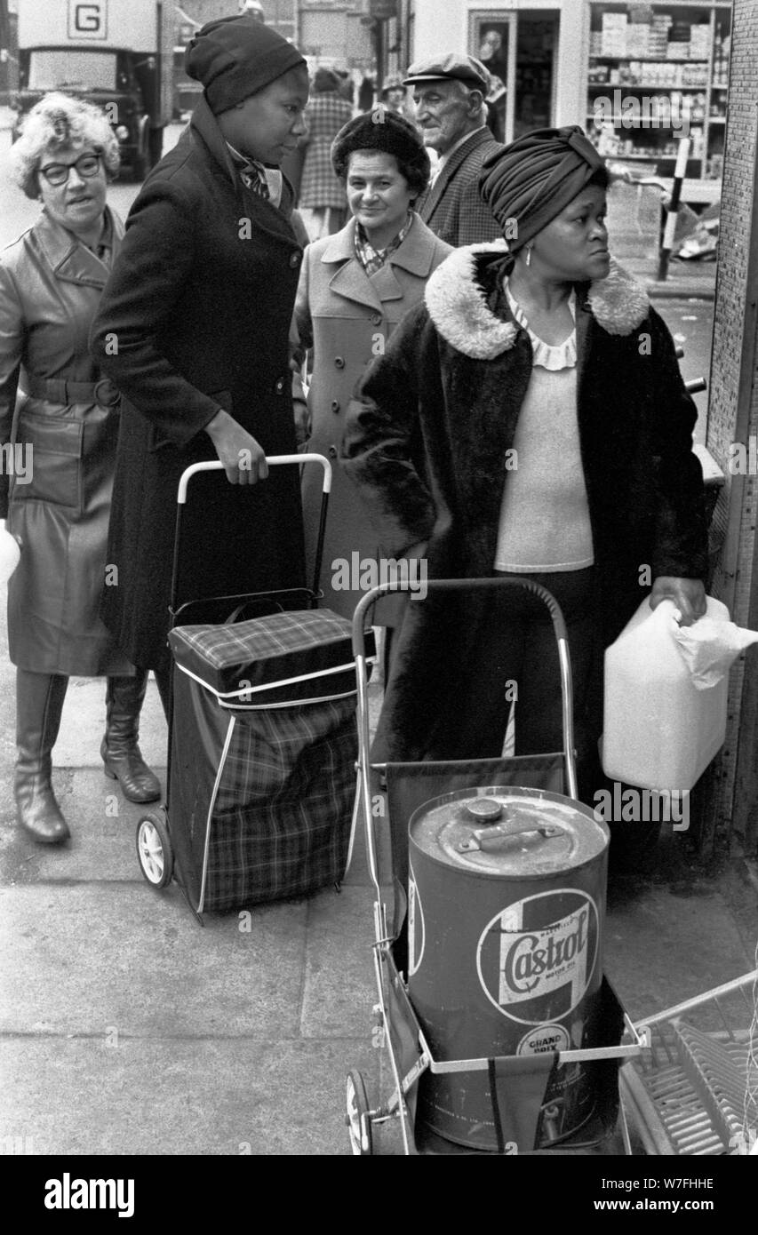 Fuel shortage 1970s UK. People queuing up to buy oil and paraffin from a corner shop so as to be able to heat their  homes south London. December 1974  England. HOMER SYKES Stock Photo