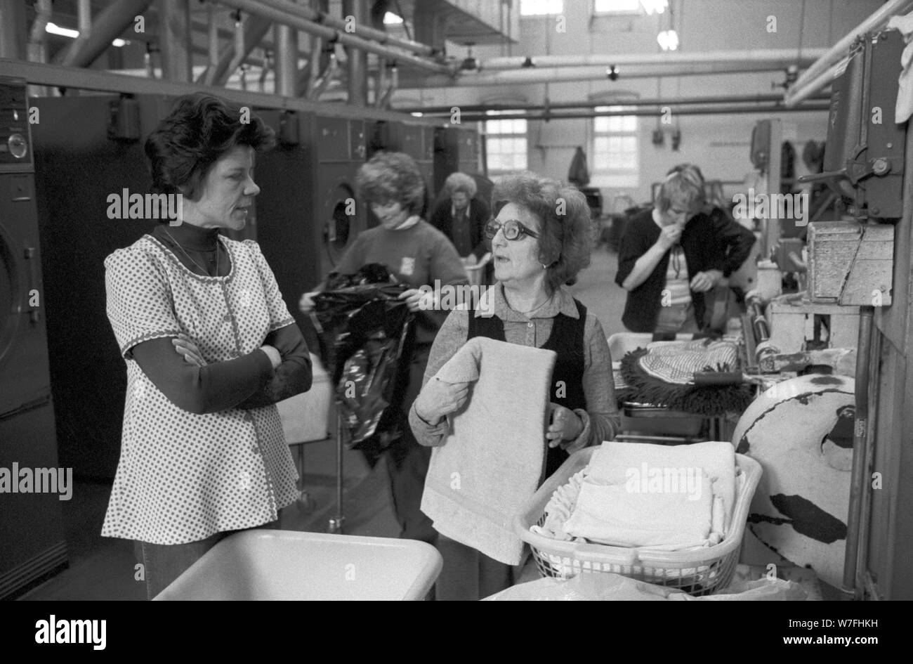 Public Laundry 1970s UK . Women taking their dirty used clothes to a public laundry to get them washed. Battersea south London 1979 70s Manager chatting with customers. England HOMER SYKES Stock Photo