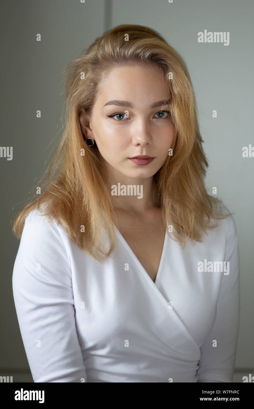 Portrait of beautiful young woman in white dress looking at camera ...