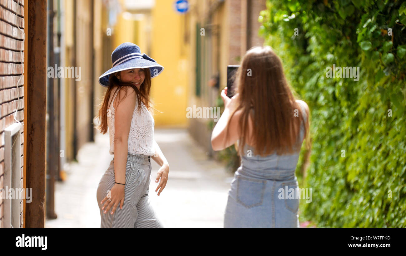 Two young women walking through the alleys - One of them posing for ...