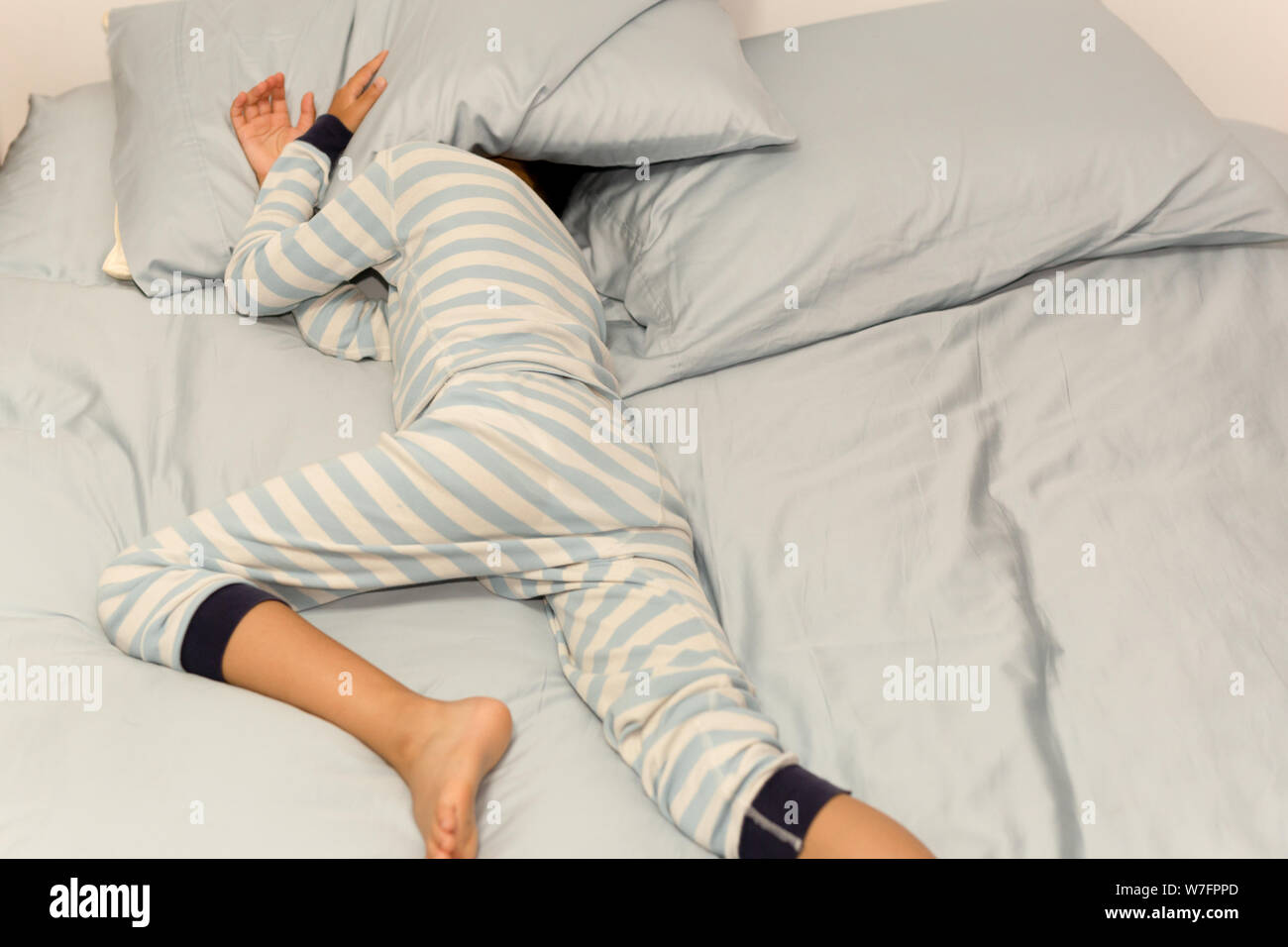 Young boy sleeping in bed with his head under pillow at home Stock ...