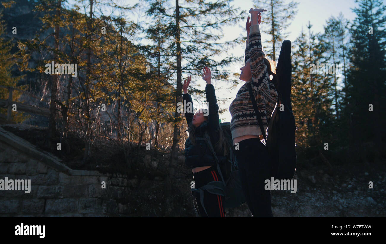 Two young women travelers standing and pulling their hands up ...