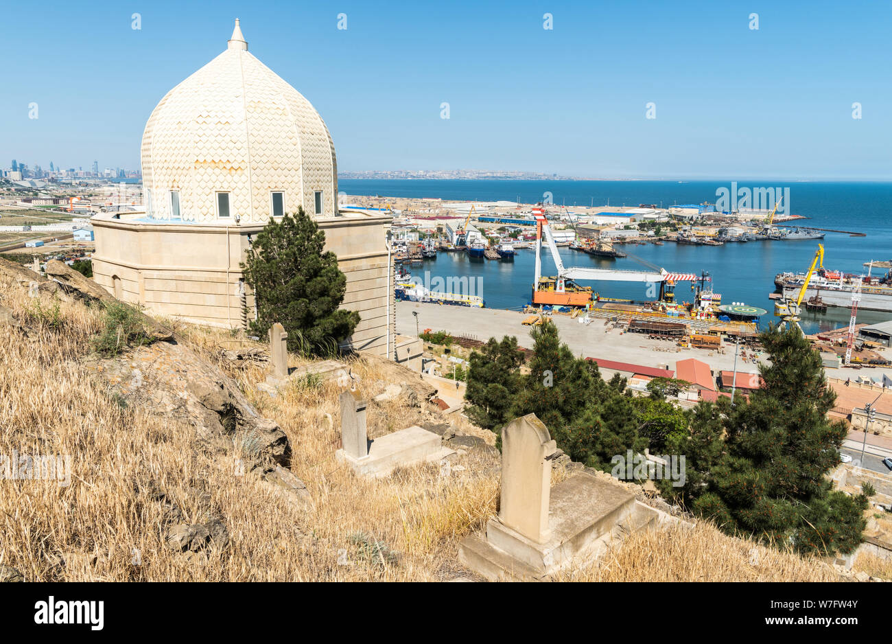 Bibi-Heybat, Baku, Azerbaijan - May 12, 2019. Bibi-Heybat shrine in the cemetery near Bibi-Heybat mosque in Baku, with shipyard facilities in the back Stock Photo