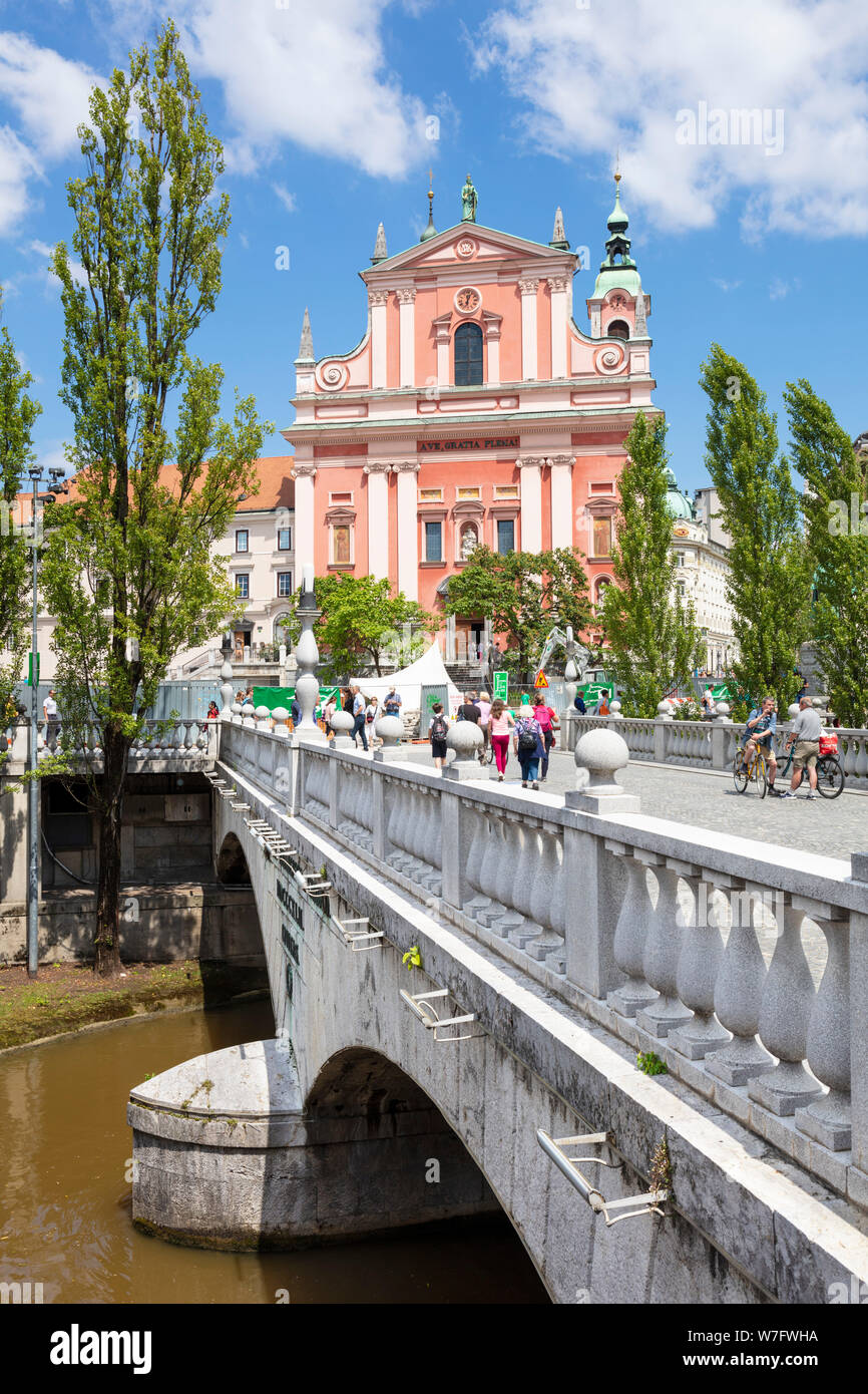 The Pink Franciscan Church in Preseren square and tourists walking over the triple bridge over the Ljubljanica river ljubljana Slovenia EU Europe Stock Photo