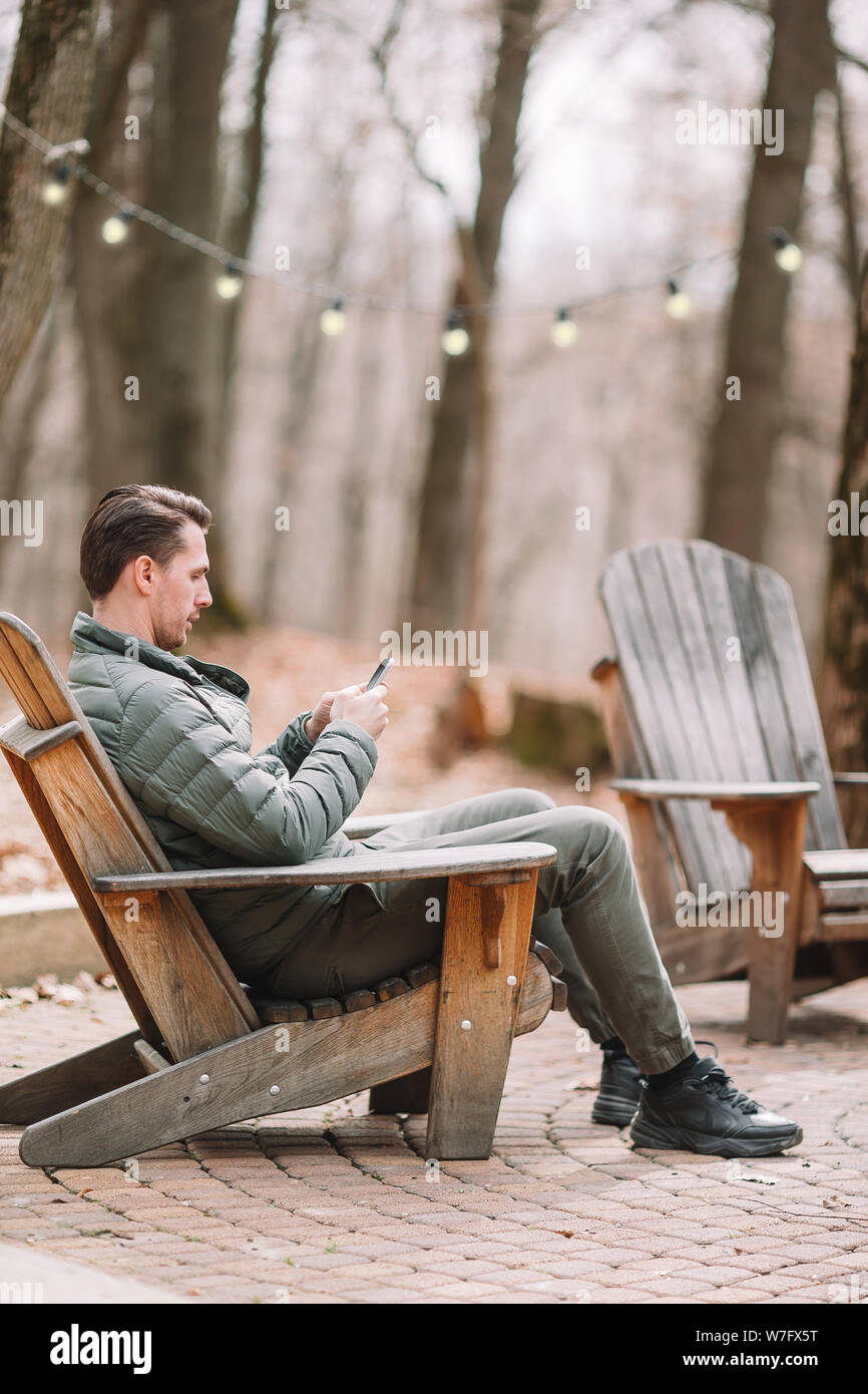 Caucasian tourist boy with cellphone outdoors in cafe. Man using mobile smartphone. Stock Photo