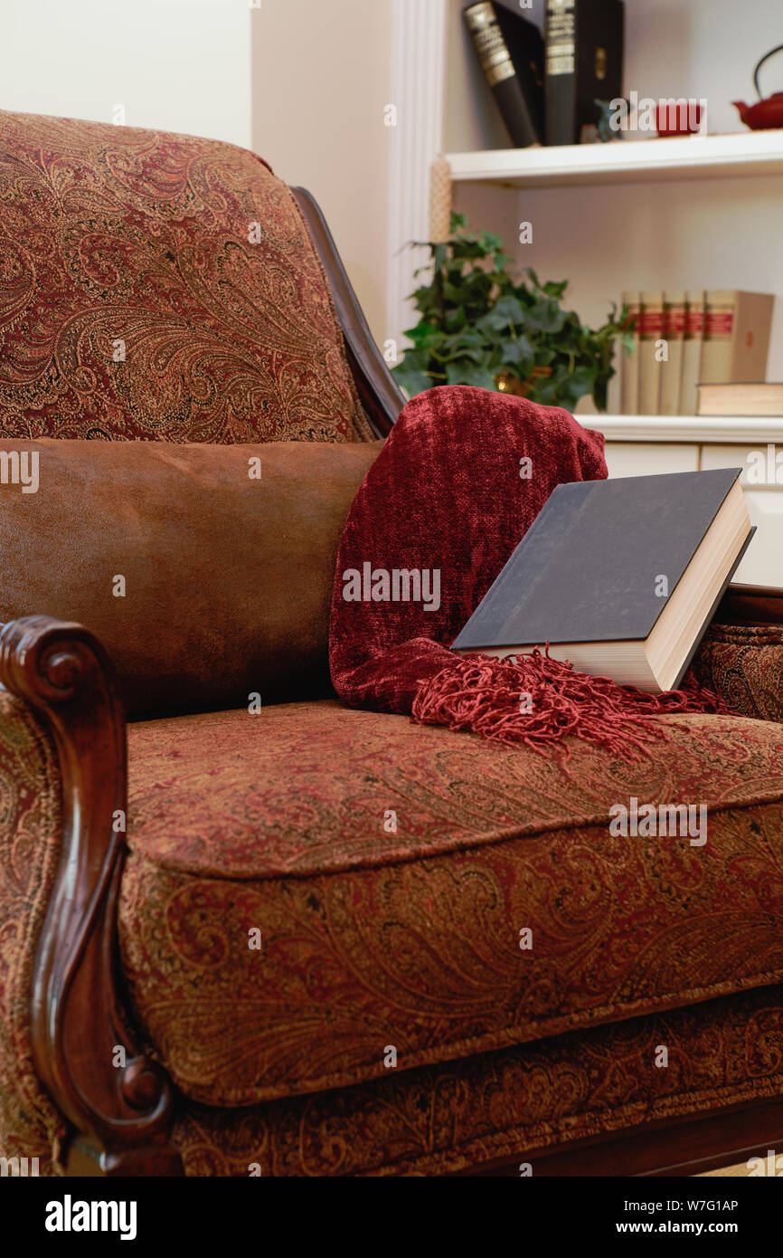 https://c8.alamy.com/comp/W7G1AP/cozy-red-and-brown-paisley-with-wood-trim-reading-chair-with-a-brown-pillow-burgundy-chenille-lap-blanket-and-book-W7G1AP.jpg