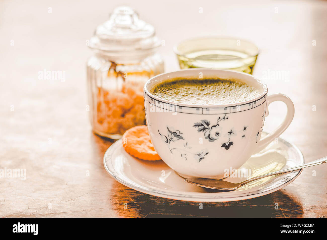green tea matcha soy latte in a china cup with brown sugar and a glass