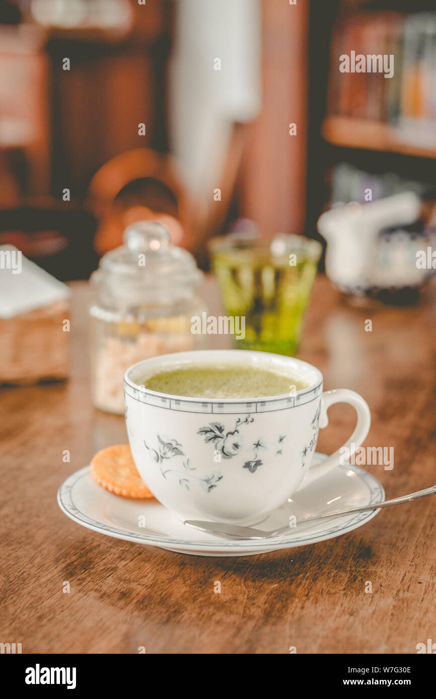 green tea matcha soy latte in a china cup with brown sugar and a glass