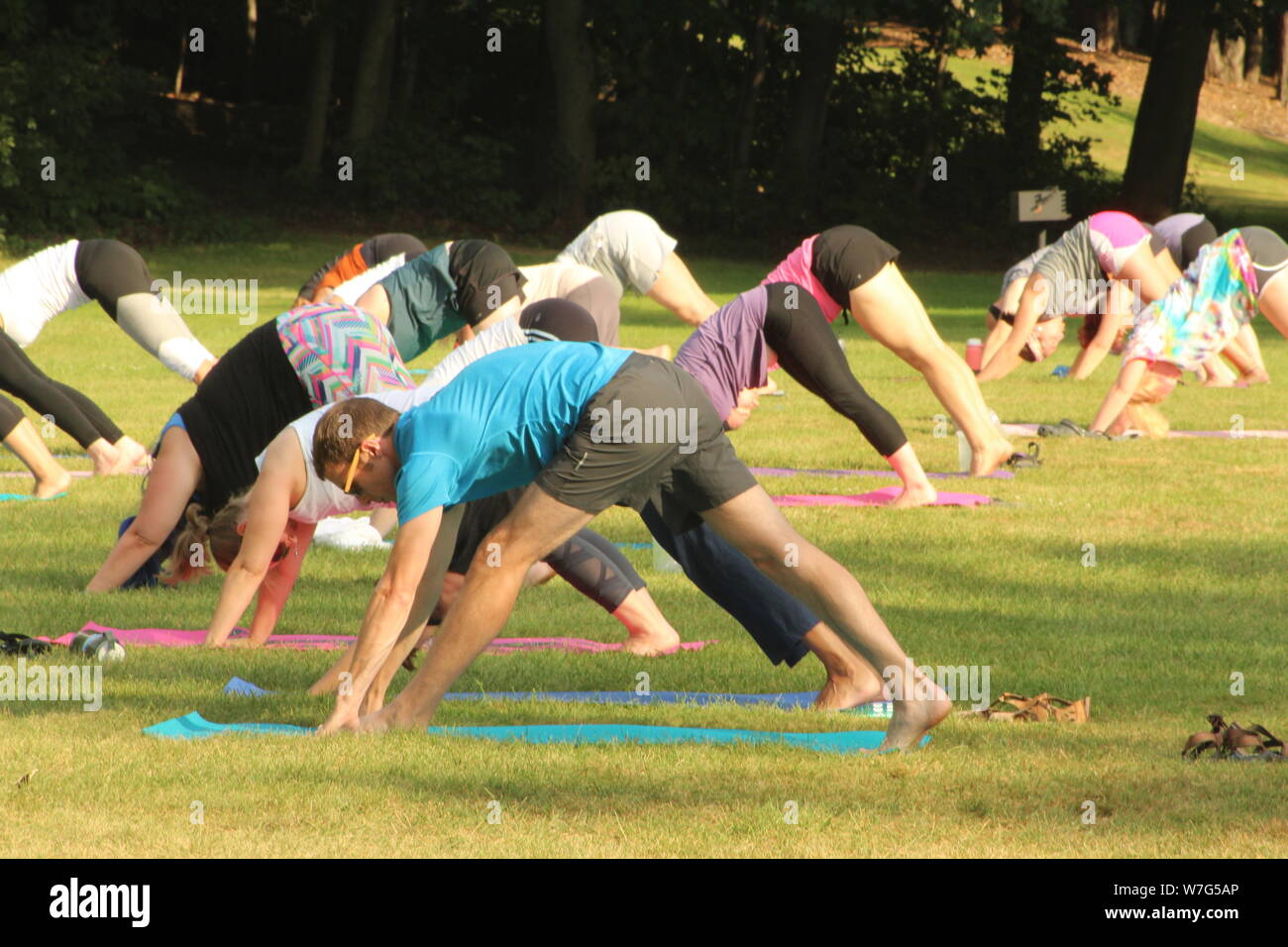 Yoga in the park attracts a crowd on a warm summer day in August. Stock Photo