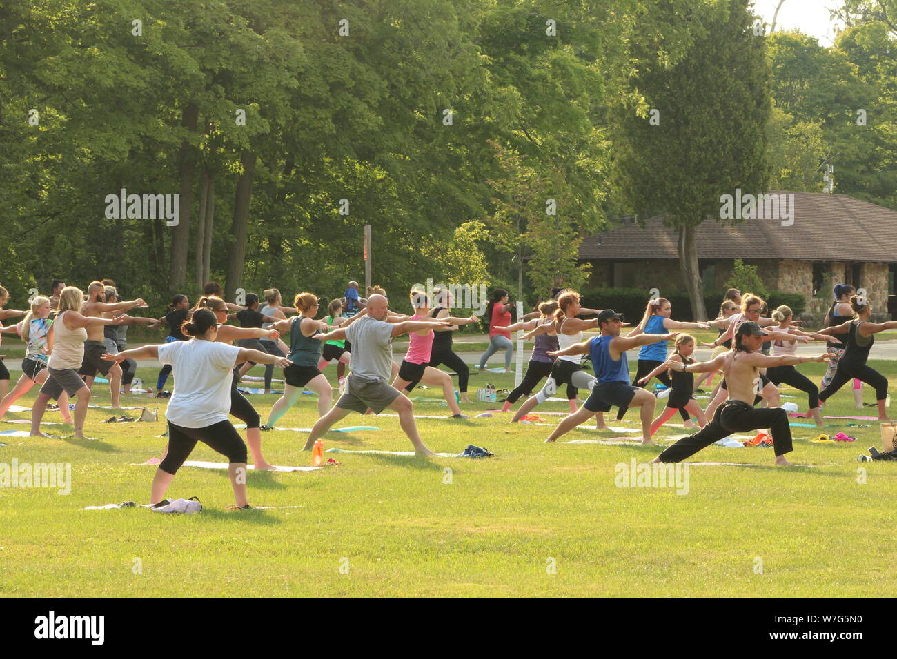 Yoga in the park attracts a crowd on a warm summer day in August. Stock Photo