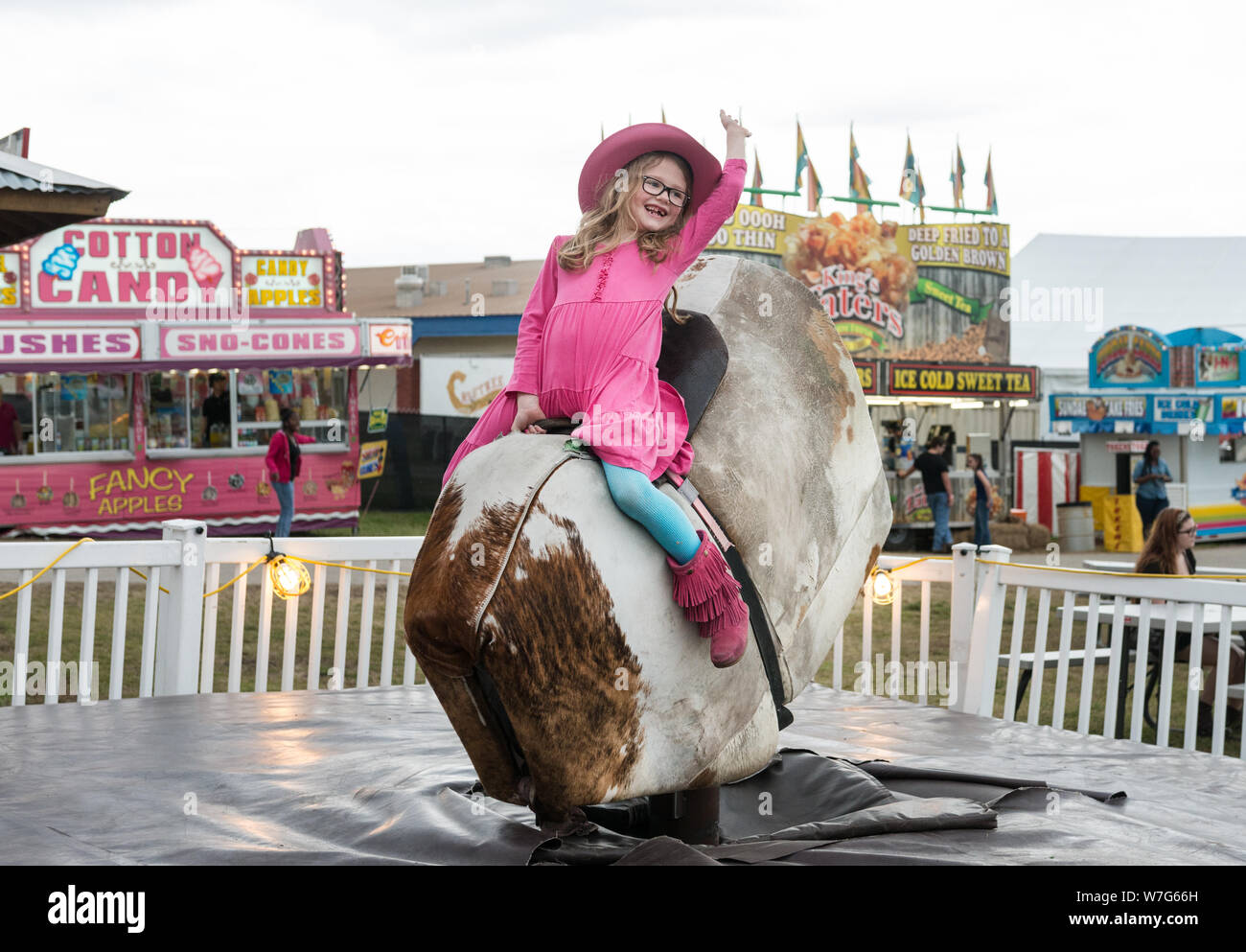Annabelle Davis gets a taste of mechanical-bull riding at Rodeo Austin, the city's annual stock show and rodeo. Austin, Texas Stock Photo