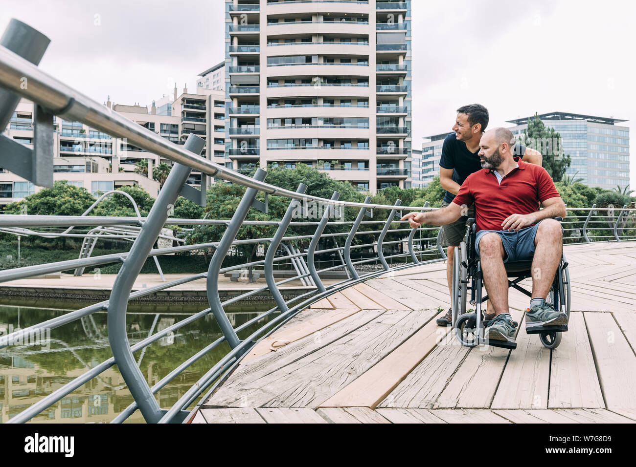 disabled man in a wheelchair talking to his friend during a walk ...