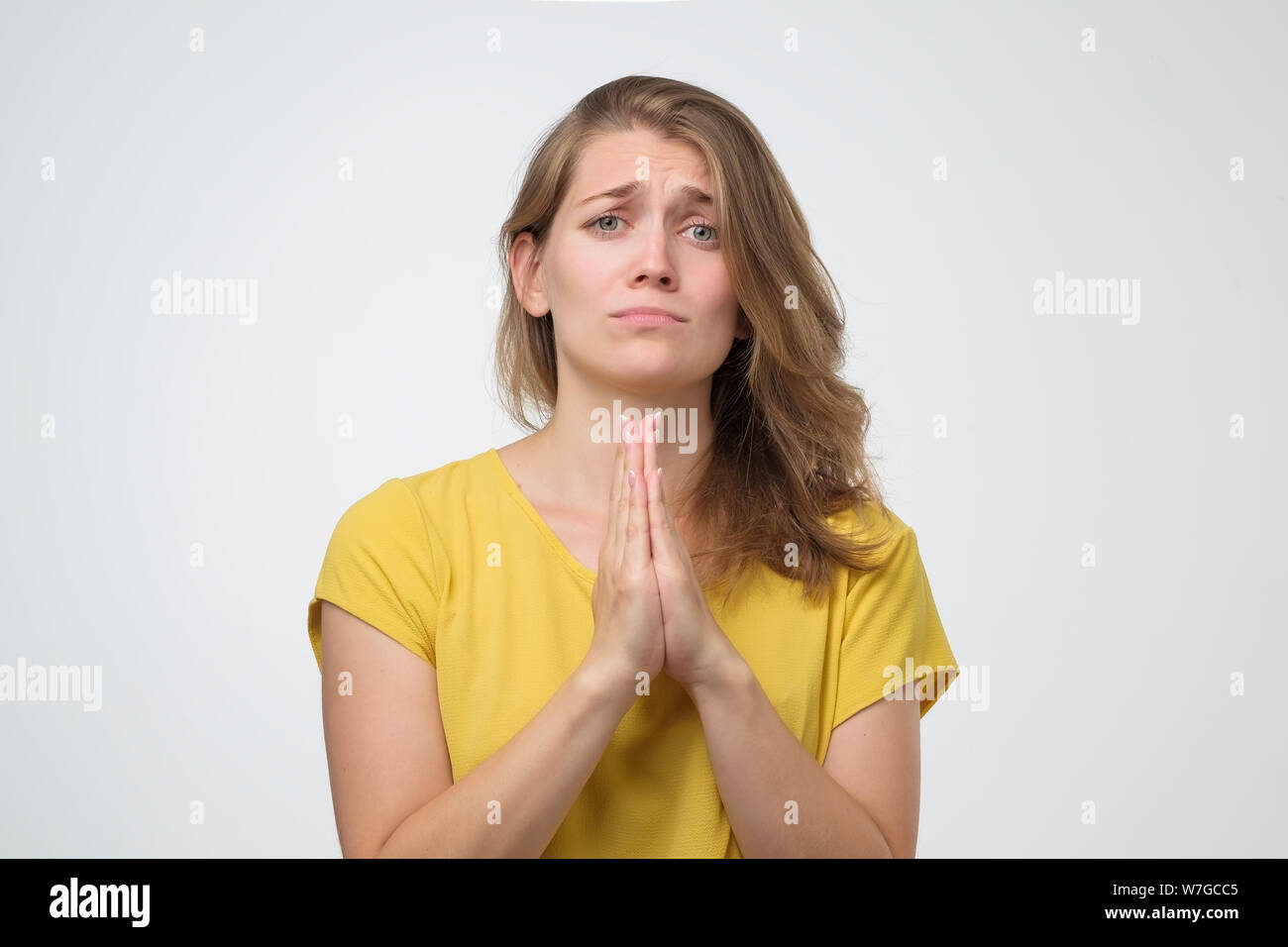 Girl, hope friends make favour. Young woman standing press palms together begging pray for help. Studio shot Stock Photo