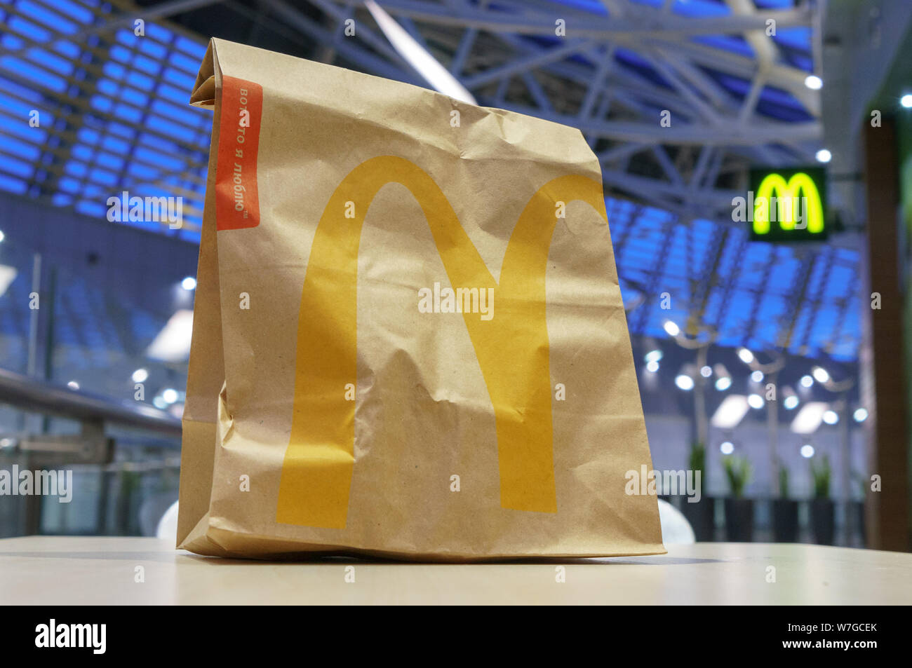 Moscow, Russia - February 07, 2019: McDonald's brown paper bag with blurred kiosk in shopping mall. Stock Photo