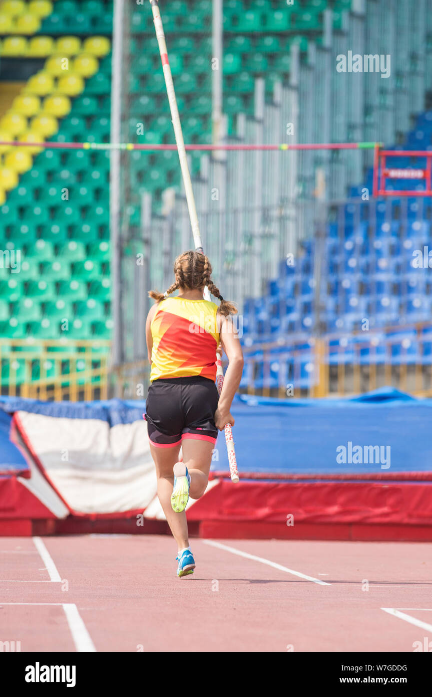 Pole vault a young woman runs up holding a pole before jumping Stock