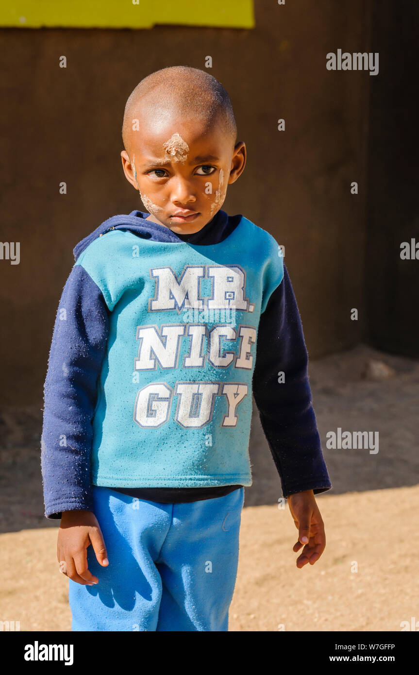 A young boy with a dirty face after playing, and wearing a top saying 'Mr Nice Guy' in his primary school in the township at Otjiwarongo, Namibia Stock Photo