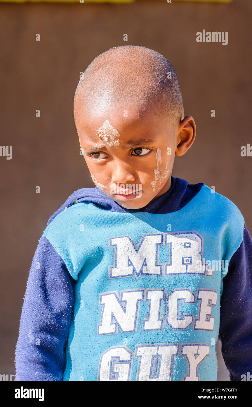 A young boy with a dirty face after playing, and wearing a top saying 'Mr Nice Guy' in his primary school in the township at Otjiwarongo, Namibia Stock Photo