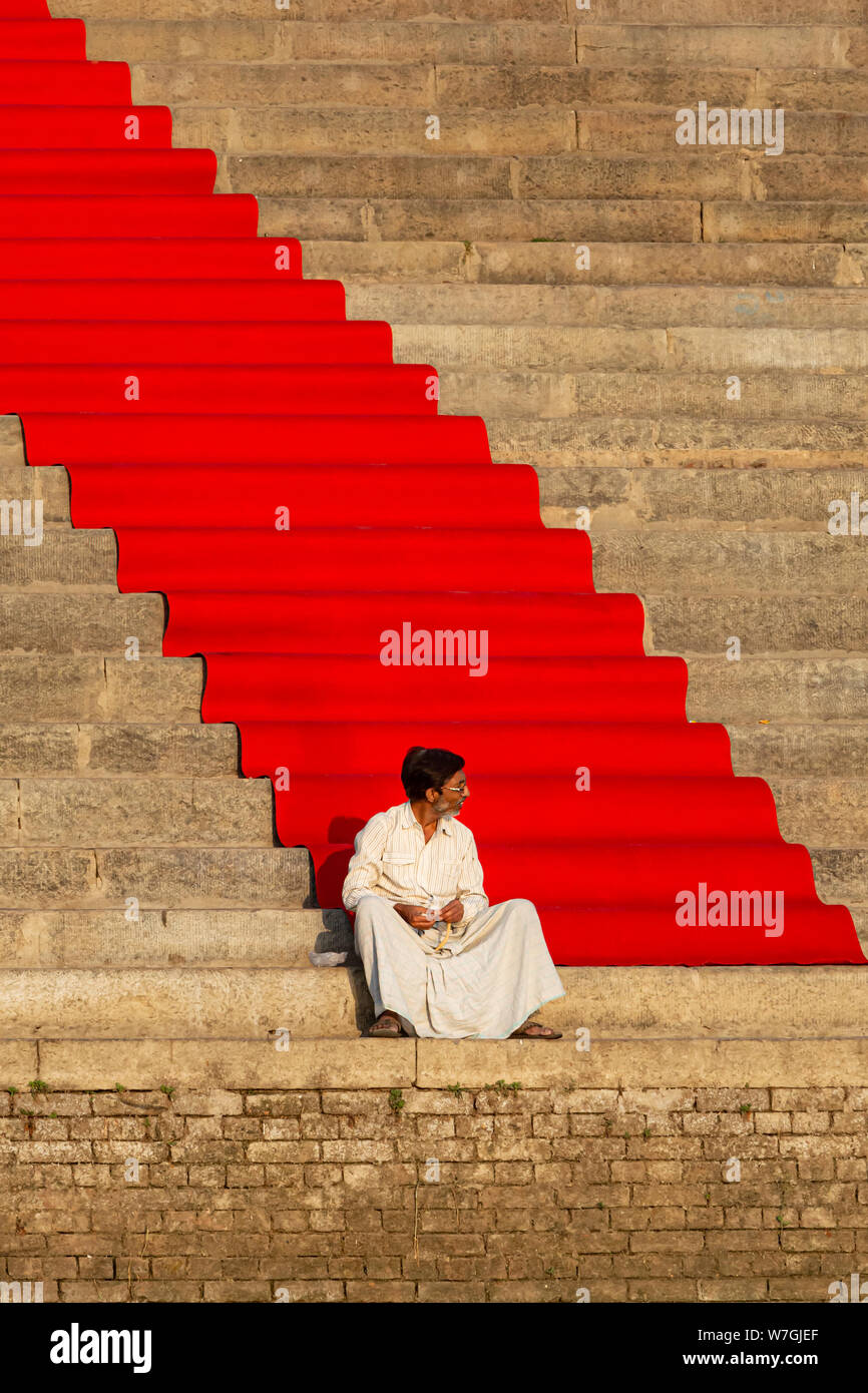 Man sat beside VIP red carpet in Varanasi Stock Photo