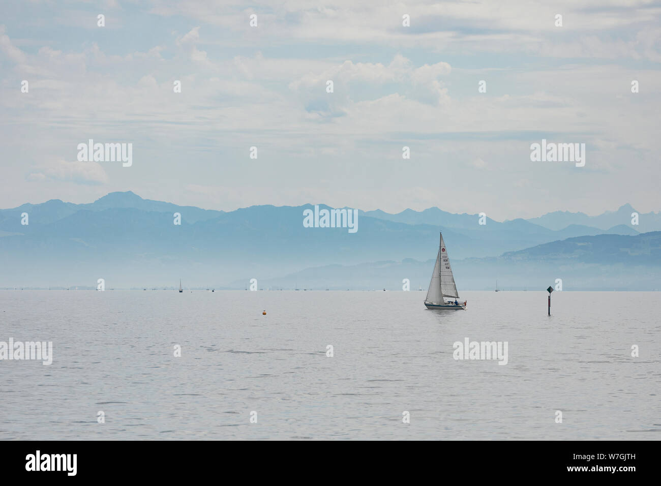 A sailboat glides in front of the Alps on Lake Constance (Bodensee) on a summer day in Friedrichshafen, Germany. Stock Photo