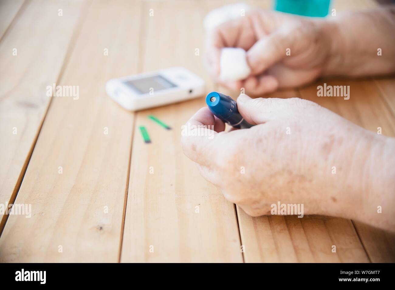 Old lady is testing blood sugar level using blood sugar test kid set - people with medical equipment concept Stock Photo