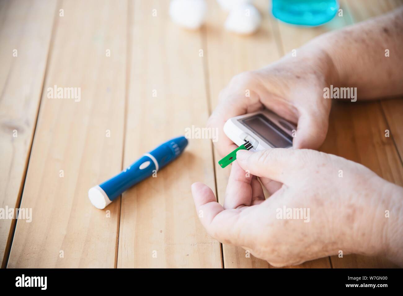 Old lady is testing blood sugar level using blood sugar test kid set - people with medical equipment concept Stock Photo