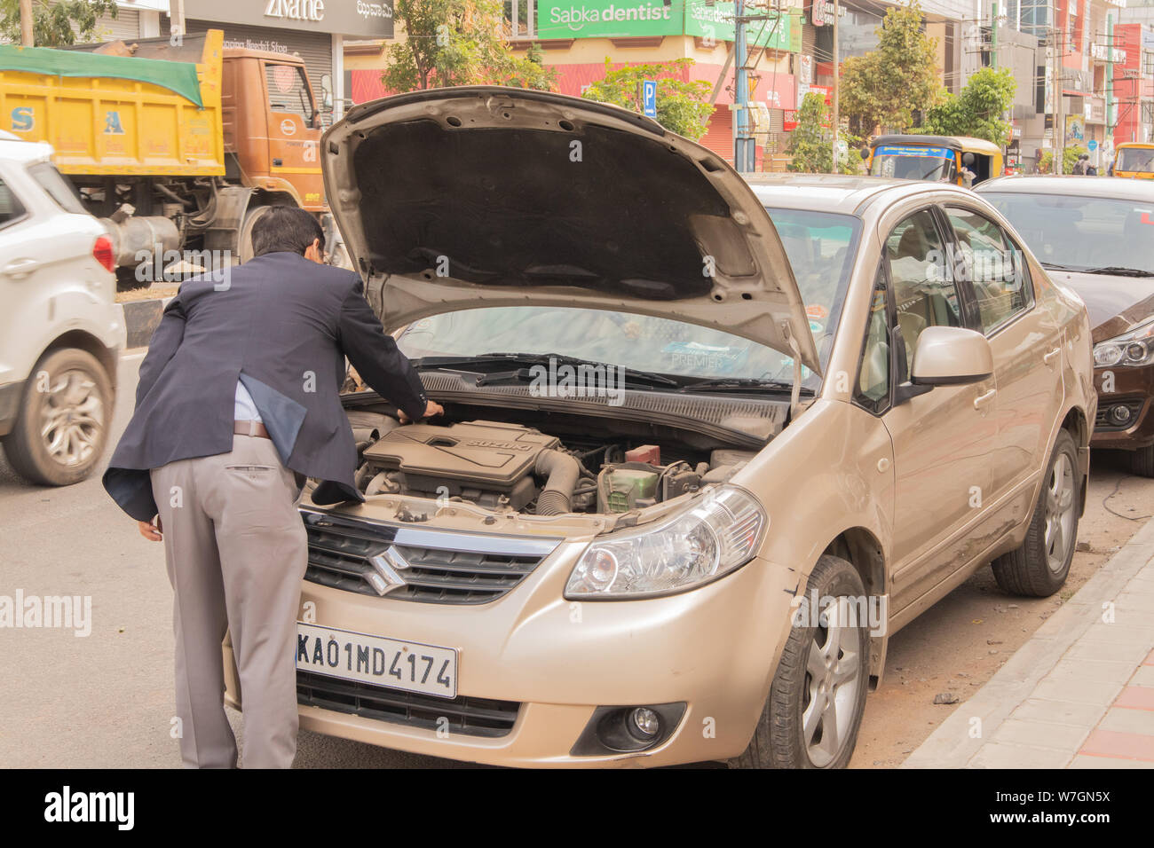 Bengaluru, India June 27,2019 : Businessman trying to inspect his broken car on road side at Bengaluru,India Stock Photo