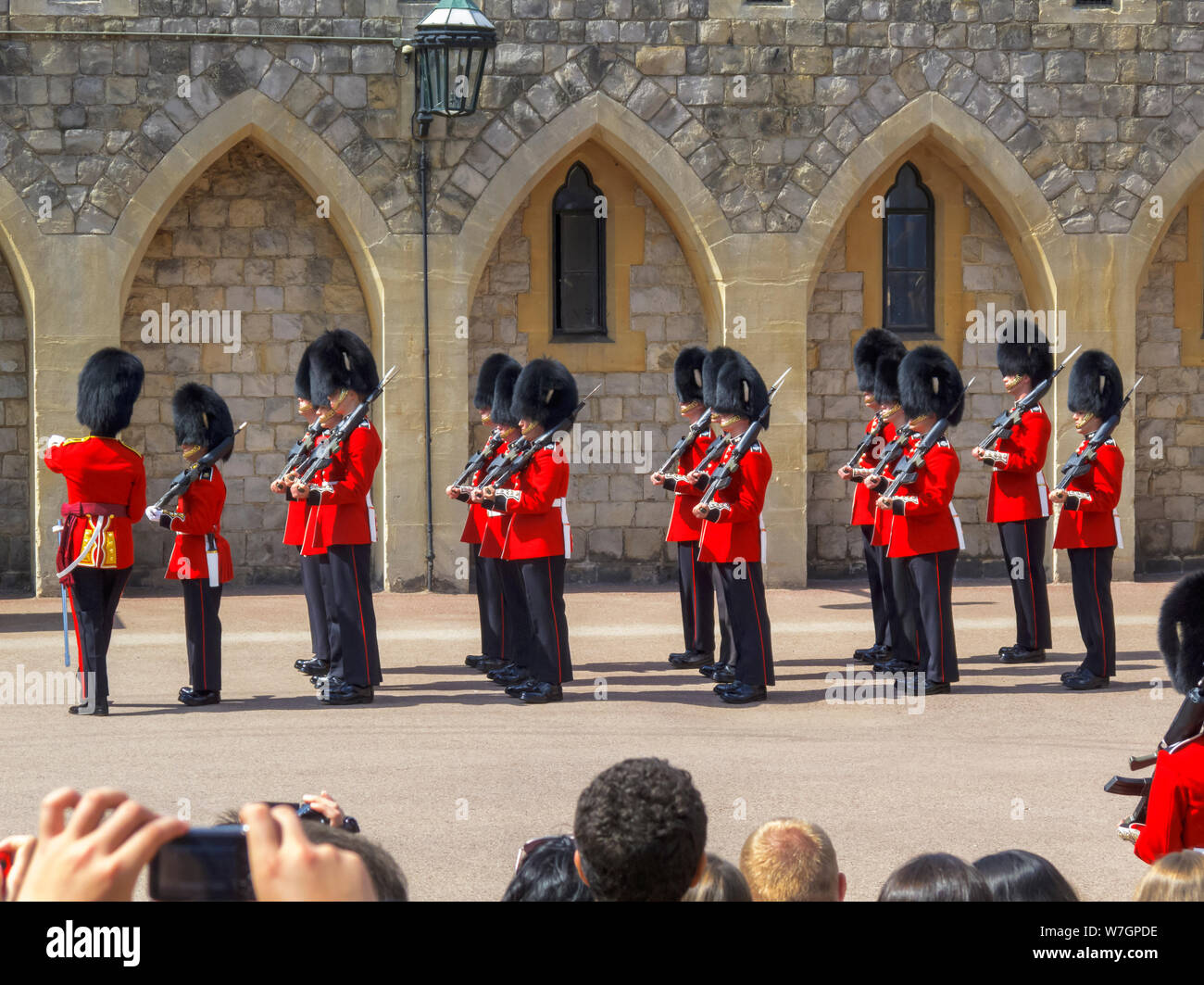 Tourists watch soldiers of the Household Troops during the changing the Castle Guard ceremony in Windsor Castle Lower Keep precincts, Windsor, UK Stock Photo