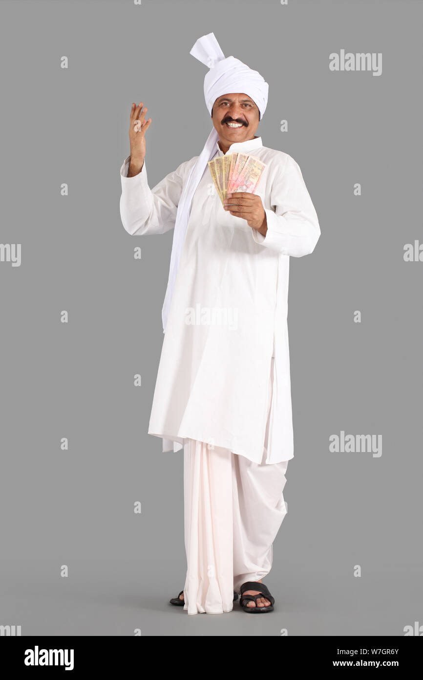Happy Indian farmer holding wood stick in hand standing in agriculture  field wearing traditional kurta dress, Smiling Man with mustache and black  hair Stock Photo - Alamy